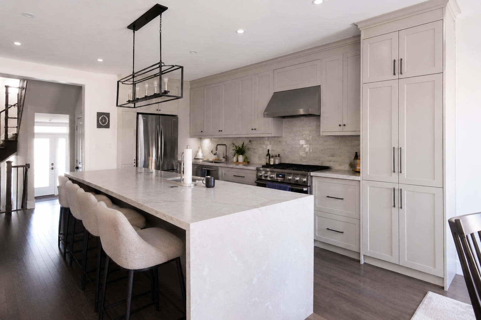 Renovated kitchen with a marble waterfall island and custom cabinetry by Summit Home Renovations
